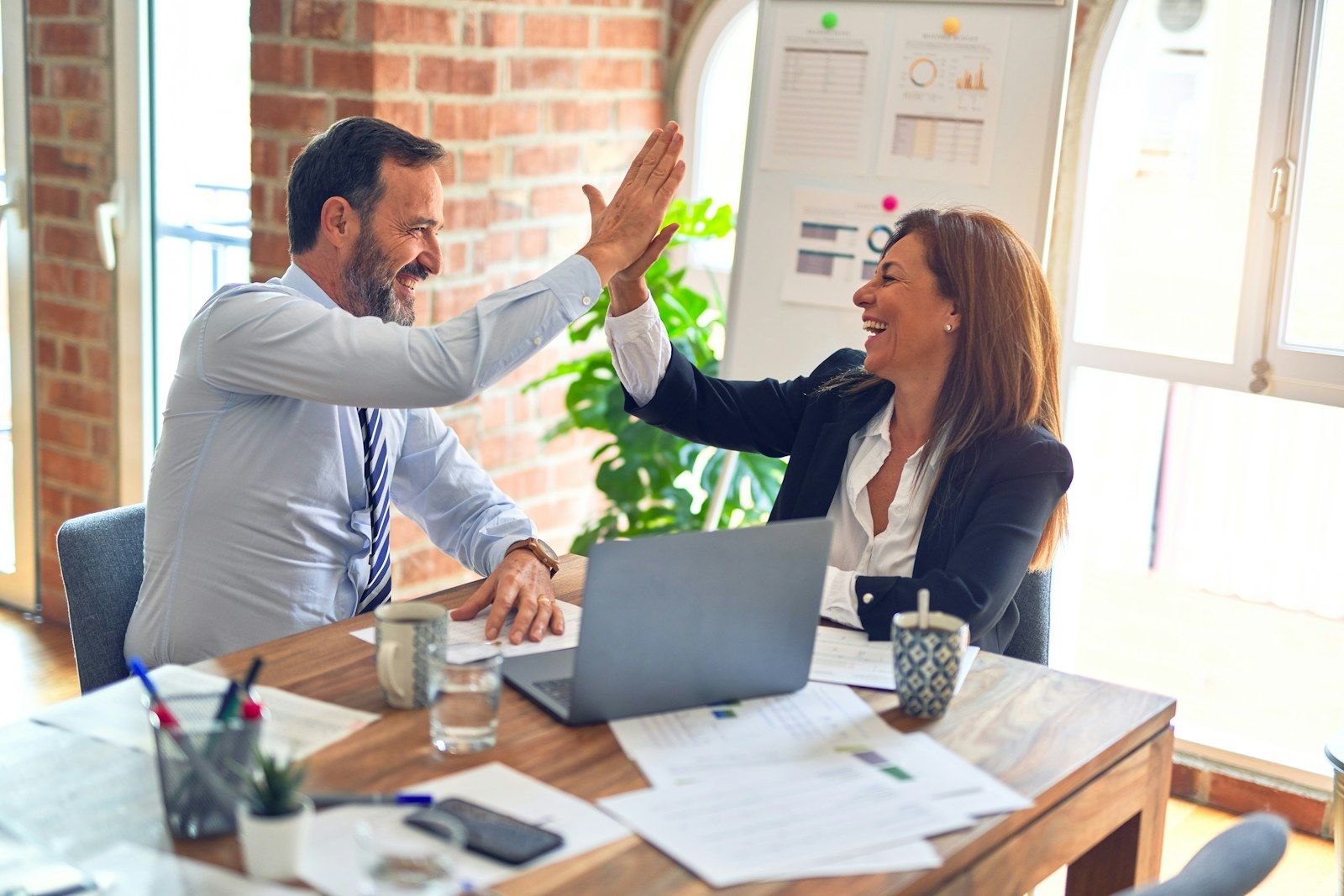 A successful handover: two colleagues high-five in the office